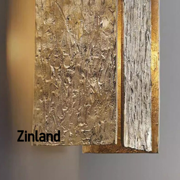 Close-up view of textured brass panels on a wall sconce, showcasing intricate craftsmanship and warm gold tones.