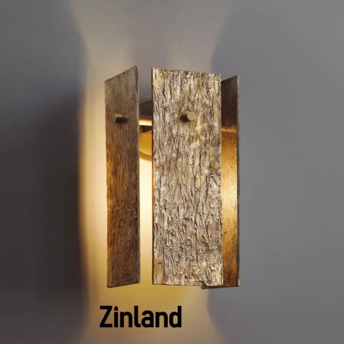 Modern brass wall light with textured artisanal panels emitting a warm ambient glow, suitable for contemporary interiors.
