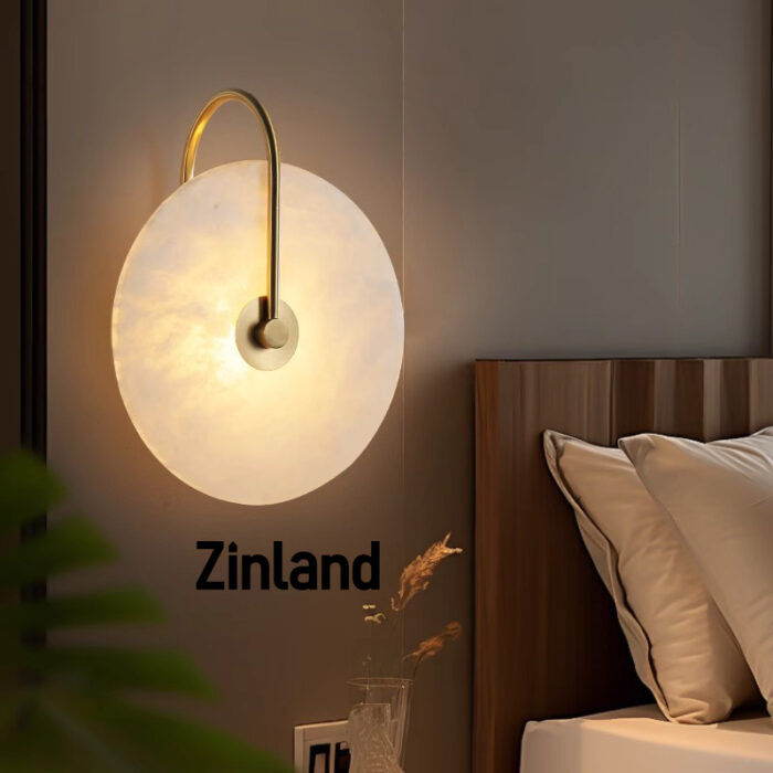 Elegant gold alabaster wall lamp with a curved brass arm, mounted beside a modern wooden bed for warm ambient lighting.