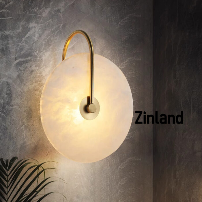 Elegant gold alabaster wall lamp with a curved brass arm, mounted on a textured wall for ambient lighting.